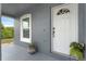 Covered front entry featuring a white front door, side window, gray siding and a decorative hanging flower pot at 7998 Harbor Bend Cir, Orlando, FL 32822