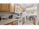 Well-lit kitchen featuring wooden cabinetry, white appliances, and tiled flooring leading to an adjacent dining area at 12220 Wild Iris Way # 103, Orlando, FL 32837