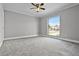 Bright bedroom featuring new carpet, ceiling fan, and a large window with a view of the outdoors at 123 Tuxpan Ln, Kissimmee, FL 34743
