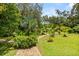 Backyard path leading through lush greenery, mature trees, and manicured lawn offering a peaceful and inviting outdoor experience at 1247 Rosemary Dr, Orlando, FL 32807