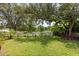 A verdant backyard featuring a white picket fence, mature trees, and well-manicured lawn providing a serene outdoor retreat at 1247 Rosemary Dr, Orlando, FL 32807