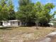 A single-story home is nestled behind mature trees and a spacious front yard at 128 N Sunland Dr, Sanford, FL 32773