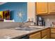 Kitchen countertop with sink and faucet, adjacent to the breakfast bar and living room with television at 13427 Blue Heron Beach Dr # 306, Orlando, FL 32821