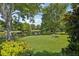 Beautiful backyard with lush green lawn, mature trees, manicured shrubs, and a picturesque pond view at 1386 Longley Pl, Deland, FL 32724