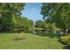 Serene backyard featuring lush lawn, mature trees, manicured shrubbery, and a tranquil pond view at 1386 Longley Pl, Deland, FL 32724