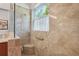 Elegant walk-in shower featuring travertine tile, bench, and large window at 1386 Longley Pl, Deland, FL 32724