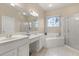 Elegant bathroom with dual sinks, soaking tub, glass shower, and arched window at 14174 Islamorada Dr, Orlando, FL 32837