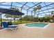 Refreshing pool with lounge chairs under an umbrella, all within a screened enclosure at 14174 Islamorada Dr, Orlando, FL 32837