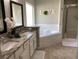 Bright bathroom featuring double sinks with granite counters, a garden tub, and a separate shower at 1428 Casterton Cir, Davenport, FL 33897