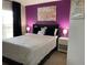 Stylish bedroom featuring a purple accent wall, large bed, and modern decor at 1428 Casterton Cir, Davenport, FL 33897