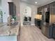 Stylish kitchen with stainless steel appliances, gray cabinetry, granite countertops, and open access to dining space at 1428 Casterton Cir, Davenport, FL 33897