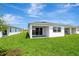 A well-maintained backyard with a covered patio, lush green grass, and a view of the adjacent properties at 1461 Santorini Way, Tavares, FL 32778