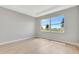 Bright bedroom with neutral walls, light wood flooring, and a large window overlooking the front yard at 1461 Santorini Way, Tavares, FL 32778