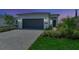 Beautiful home exterior with a gray garage door, manicured landscaping, and a brick driveway at 1461 Santorini Way, Tavares, FL 32778