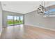 Bright living room with modern light fixture, gray walls, and sliding glass doors to the outdoor space at 1461 Santorini Way, Tavares, FL 32778
