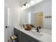 Bathroom with double sinks, gray cabinets, and a large mirror at 15408 Lebeau Loop, Winter Garden, FL 34787