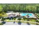 Aerial view of community pool area surrounded by lush greenery, featuring a cabana, sun loungers, and palm trees at 15408 Lebeau Loop, Winter Garden, FL 34787