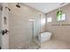 Beautiful bathroom with a glass enclosed shower, soaking tub, neutral tiling, and a plant hanging in front of the window at 15702 Vetta Dr, Bella Collina, FL 34756
