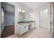 Bright bathroom features double vanity with white cabinets, grey countertop, large mirror, and a view into the glass shower at 15702 Vetta Dr, Bella Collina, FL 34756
