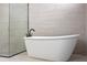 Close up of a white free-standing bathtub with black hardware adjacent to the glass enclosed shower with pebble stone floor at 15702 Vetta Dr, Bella Collina, FL 34756