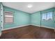 Neutral bedroom with aqua walls, two large windows, wood floors, and white trim throughout at 15702 Vetta Dr, Bella Collina, FL 34756