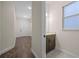 Hallway featuring wood flooring leading to a well-lit bathroom with patterned tile at 15702 Vetta Dr, Bella Collina, FL 34756