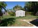A storage shed sits on a grassy lawn with a stone path in the backyard under a bright, blue sky at 1615 Crestwood Dr, Orlando, FL 32804
