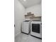 Modern laundry room with side-by-side washer and dryer and floating shelves at 1773 Groveline Rd, St Cloud, FL 34771