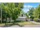 The property's exterior is partially obscured by trees and landscaping, featuring a white picket-style feature and a metal roof at 201 W Washington St, Minneola, FL 34715