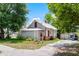 The exterior of the house features a brick foundation, white siding, and a metal roof, framed by lush greenery and a driveway at 201 W Washington St, Minneola, FL 34715
