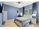 Blue bedroom with large bed and a desk space, featuring a ceiling fan and ample lighting at 209 Luxmore Rd, Groveland, FL 34736