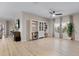 Bright and airy living room featuring light wood floors, built-in shelves, a ceiling fan, and large windows with elegant curtains at 209 Luxmore Rd, Groveland, FL 34736