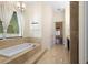 Bathroom showcasing a soaking tub with tile surround, window with blinds, and marble floors at 215 Juniper Ridge Ct, Sanford, FL 32771