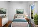 Bright bedroom with white walls, wood floors, a neutral headboard and a landscape painting above the bed at 215 Juniper Ridge Ct, Sanford, FL 32771