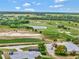 Scenic aerial view of the community golf course, driving range and pond with golfers, golf carts and lush greenery at 23820 Sardinia Dr, Sorrento, FL 32776