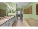 Well-lit bathroom featuring double sinks, a soaking tub, and a glass-enclosed shower at 23820 Sardinia Dr, Sorrento, FL 32776