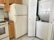 Convenient kitchen with a white refrigerator and stacked washer/dryer for space-saving efficiency at 2524 Woodgate Blvd # 201, Orlando, FL 32822