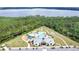 An aerial view showcasing the community pool and clubhouse, nestled amidst lush greenery and a serene lake backdrop at 2834 Common Crane Ct, St Cloud, FL 34773