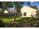 View of home's backyard with a yellow exterior, small patio, lush green lawn, and mature trees at 30101 Pga Dr, Sorrento, FL 32776