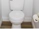 Close-up of a white toilet with a wood-look vinyl floor and a roll of toilet paper at 30101 Pga Dr, Sorrento, FL 32776
