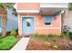Close-up of a peach-colored home showcasing a blue front door, shutters, and well-manicured landscaping at 3062 Pirate Way, Kissimmee, FL 34747