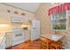 Functional kitchen with white appliances, a cozy breakfast nook, and charming floral wallpaper at 3987 Lancashire Ln # 3987, Longwood, FL 32779