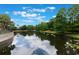 Picturesque view of the pond, with reflections of trees and clouds on the water at 6107 Metrowest Blvd # 104, Orlando, FL 32835