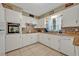 Well-lit kitchen showcasing a mosaic backsplash, white cabinets, and modern appliances by a bright window at 806 Bear Lake Rd, Apopka, FL 32703