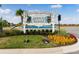 Community entrance sign with vibrant landscaping featuring flowers and palm trees at 867 Bama Breeze Dr, Daytona Beach, FL 32124