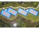 Aerial view of vibrant blue tennis courts nestled within lush greenery and winding pathways at 867 Bama Breeze Dr, Daytona Beach, FL 32124