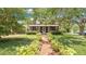 Inviting front exterior of a brick home with a covered porch, surrounded by lush landscaping and a brick walkway at 900 S Palmetto Ave, Sanford, FL 32771