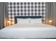 Bright bedroom features stylish buffalo check accent wall, plush bedding, and elegant lighting at 9038 Sunshine Ridge Loop, Kissimmee, FL 34747