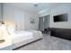 Modern bedroom with light gray carpet, white door, black dresser, bench, chair, and mounted TV at 9038 Sunshine Ridge Loop, Kissimmee, FL 34747