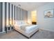 Stylish bedroom featuring a queen bed with striped accent wall, gray carpet, and next to a bathroom at 9038 Sunshine Ridge Loop, Kissimmee, FL 34747